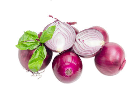 Several whole bulbs of red onion and one bulb cut in half with twig of a green basil on a light backgroundの写真素材
