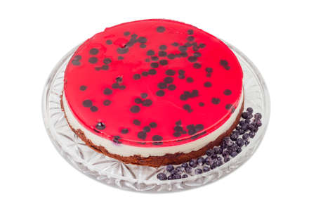 Layered cake with layers of sponge cake, milk jelly, berry jelly and separately frozen berries on a glass cake serving dish on a light backgroundの写真素材