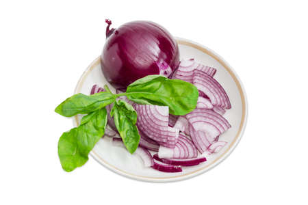 Chopped red onion, one whole peeled from the husk bulb and twig of green basil on a saucer on a light backgroundの写真素材