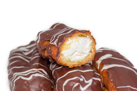 One half and several whole eclairs with whipped cream and chocolate icing closeup on a light backgroundの写真素材