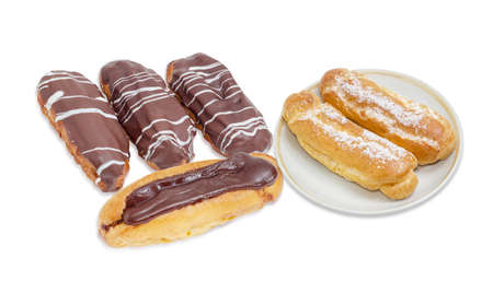 Several eclairs with different chocolate icing and two eclairs with sugar sprinkling on saucer on a...
