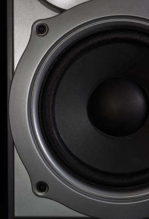 Fragment of a woofer of a home loudspeaker in silvery housing closeup on the dark backgroundの写真素材