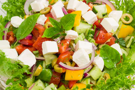 Greek salad decorated with lettuce and basil leaves in a glass salad bowl closeup
の写真素材