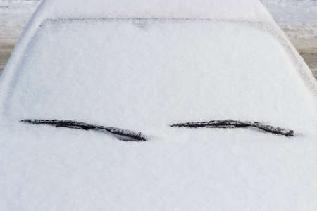 Fragment of car with hood, windshield and roof covered with fluffy snowの写真素材