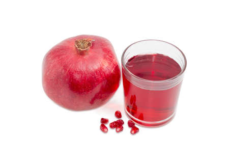 Pomegranate juice in a glass, one ripe whole pomegranate and several pomegranate seeds on a light backgroundの写真素材