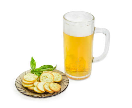 Beer glassware with lager beer, rusks with basil and pesto sauce flavor and twig of basil on a saucer on a light backgroundの写真素材