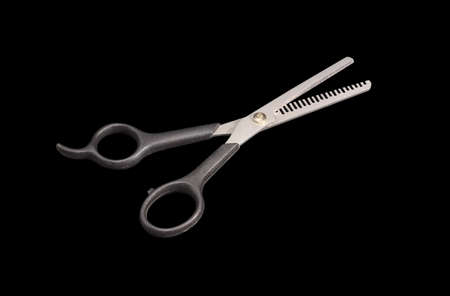 Pair of hairdressing texturizing shears with one blade with teeth on the edge on a dark background