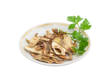 Dried boletus and twig of a parsley on saucer on a light backgroundの写真素材