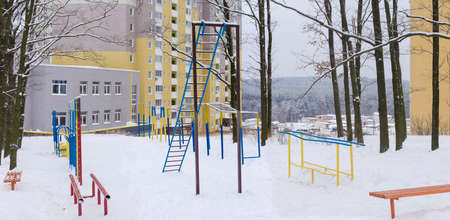 Panorama of outdoor gym in winter public park coverd snow on the background of modern multistory apartment complex
の写真素材