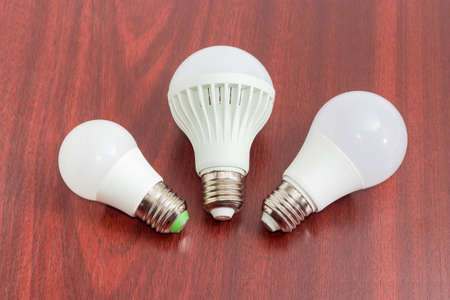 Three different domestic light emitting diode lamp with a sized E27 male screw base on a dark wooden surfaceの写真素材