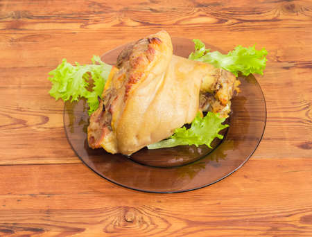 Baked ham hock with lettuce on a glass dish on a surface of old wooden planks
の写真素材