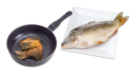 Several fried slices of carp on an aluminium cast frying pan with ceramic non-stick coating and whole frozen carp on a white square dish beside on a light background
の写真素材