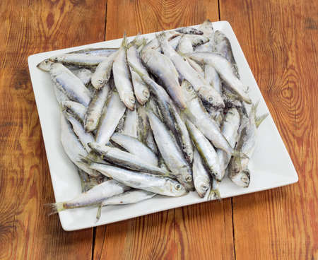 Frozen baltic herring with icy glaze on a square white dish on an old wooden surface
の写真素材
