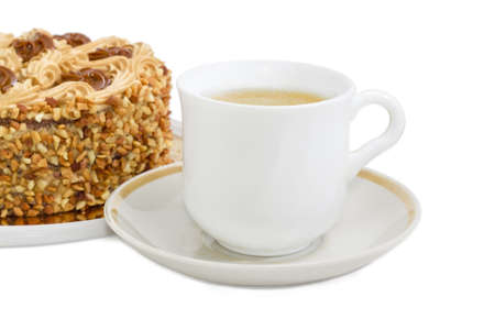 White cup with coffee with cream on a background of sponge cake, decorated with butter cream and sprinkled with grated nuts on a light background
の写真素材
