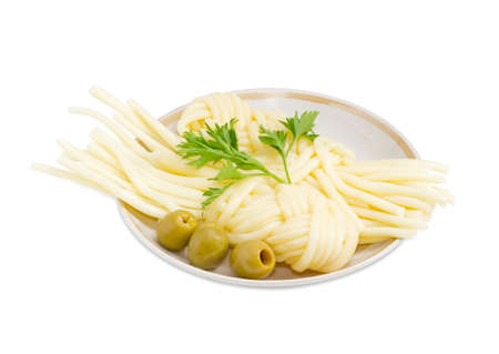 Two portions of the mozzarella cheese in the form of strings, twisted in a shape of a plait, several green olives and twig of parsley on the saucer on a light backgroundの写真素材
