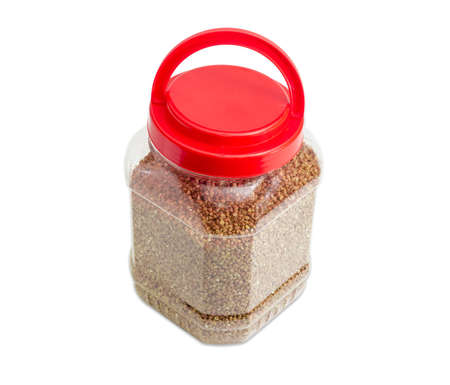 Buckwheat groats peeled from the husk in the transparent plastic container with a red cover on a light backgroundの写真素材