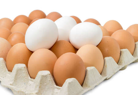 Brown chicken eggs in the cardboard egg tray and white eggs from above closeup on a light backgroundの写真素材