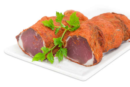 Two pieces of dried pork tenderloin and twig of parsley on a white dish closeup on a light backgroundの写真素材