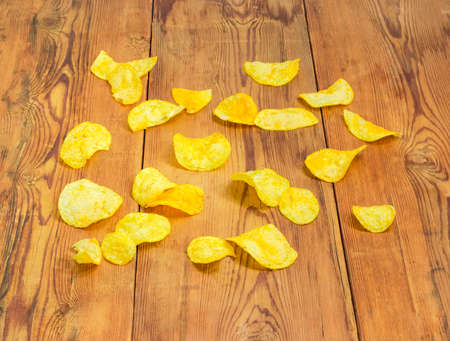 Potato chips scattered on the surface of the old darkened by time wooden planksの写真素材