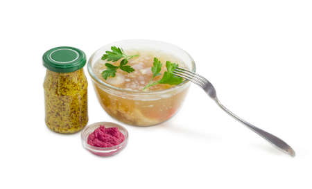 Pork aspic decorated with twigs of parsley in the glass bowl, fork, beet horseradish sauce in the small bowl, French mustard in the small glass jar on a light background の写真素材
