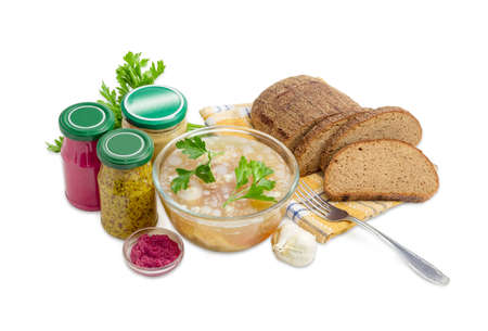 Pork aspic decorated with twigs of parsley in the glass bowl, brown bread, fork, beet horseradish sauce, mustard, French mustard in small glass jars on a light background 
の写真素材