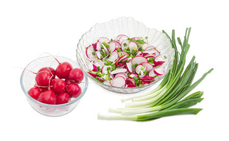 Vegetable salad of the fresh sliced red radish, green onion in transparent glass salad bowl and separately whole red radish in glass bowl and bundle of the green onion on a light background
の写真素材