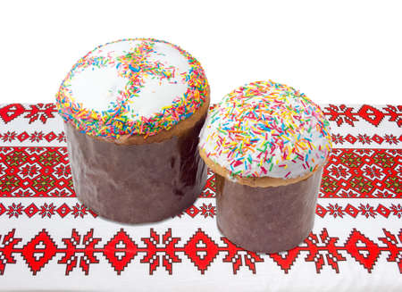 Two Easter cakes different sizes decorated with white icing and colorful sugar decors, wrapped in...