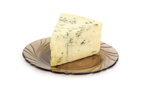 Piece of crumbly blue cheese made of a sheep milk on the dark-colored glass saucer closeup on a light backgroundの写真素材