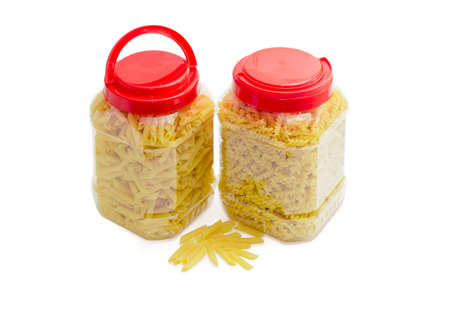 Uncooked dried spiral pasta and cylinder-shaped pasta in two transparent plastic containers with the red covers on a light backgroundの写真素材