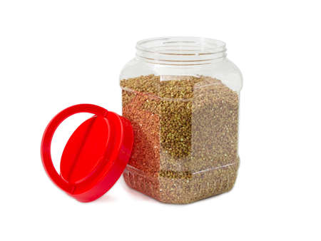 Buckwheat groats peeled from the husk in the transparent plastic container with the open red cover on a light backgroundの写真素材