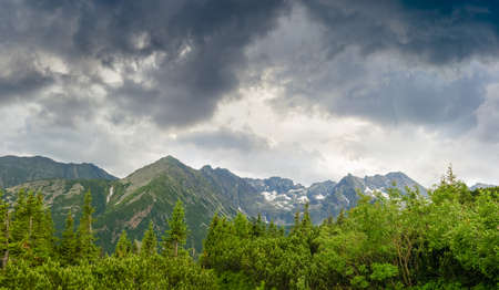 Craggy mountain massif with snow patches and forest in the foreground on the background of the sky with storm clouds in the Tatra Mountainsの写真素材