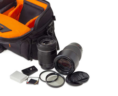 Two different photo lenses and some other photo accessories against the background of the fragment...