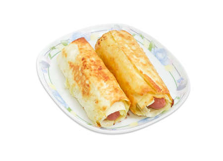 Two cooked sausage rolls made of the Vienna sausages wrapped in puff pastry on dish on a light backgroundの写真素材