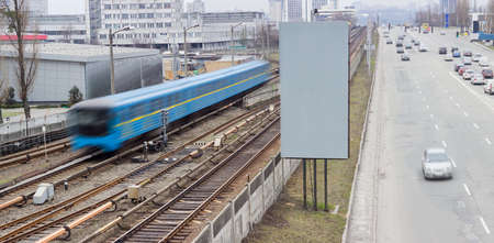 Train of a metro system moving on the overground part of the subway line and city street with moving cars beside 
の写真素材
