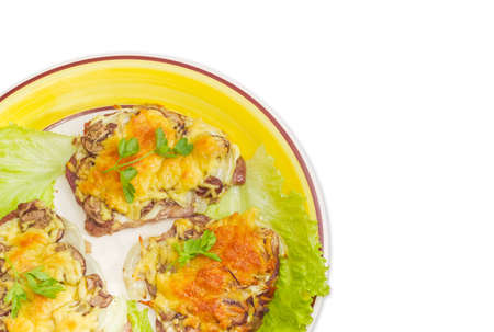 Fragment of the dish with several pork chops baked with onion, mushrooms and cheese and decorated with parsley and lettuce leaves on a light backgroundの写真素材