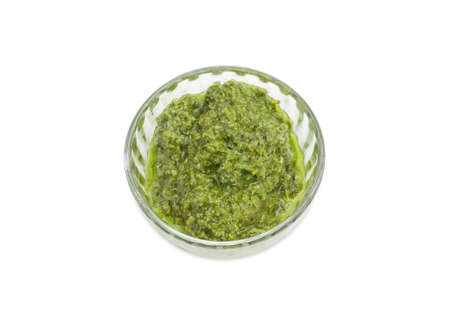 Top view of the sauce basil pesto in the small glass bowl on a white backgroundの写真素材