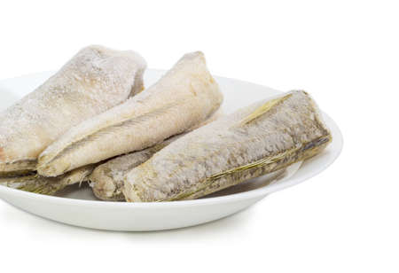 Fragment of white dish with several carcasses of the frozen saltwater fish notothenia without of a...