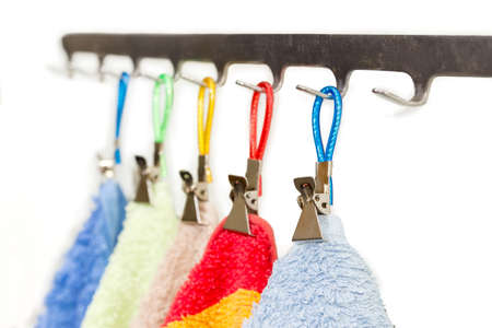 Metal clothespins for towels with rings for hanging and different towels on them hang on a hooks of hanger at shallow depth of fieldの写真素材