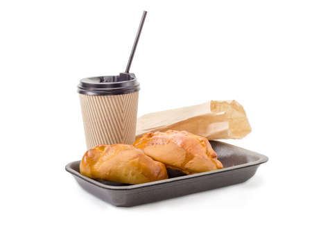 Two small sweet pies with cottage cheese toppings on a foam food container, tea in the disposable paper cup with plastic lid and drinking straw and fast food brown paper bag on a white backgroundの写真素材