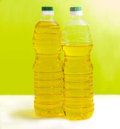 One full and one partially filled plastic bottles of the sunflower oil on an yellow background
の写真素材