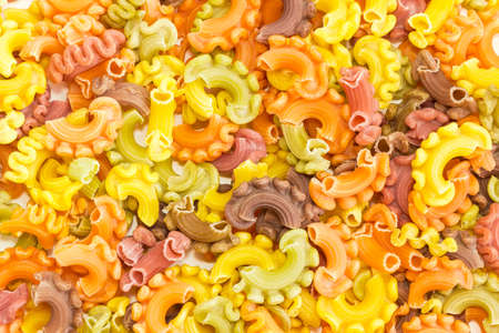 Background of the uncooked dried colored short curly pasta closeupの写真素材