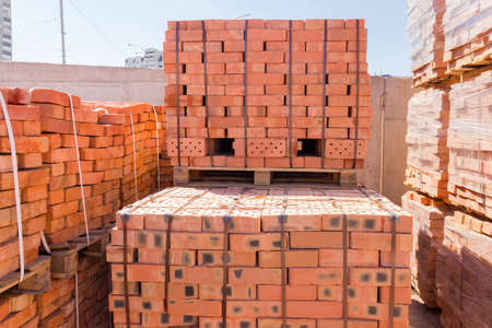Wooden pallets of the red bricks of varying quality on an outdoor warehouse 