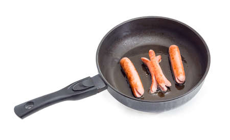 Three vienna sausages on the frying pan with ceramic non-stick coating during frying on a white backgroundの写真素材