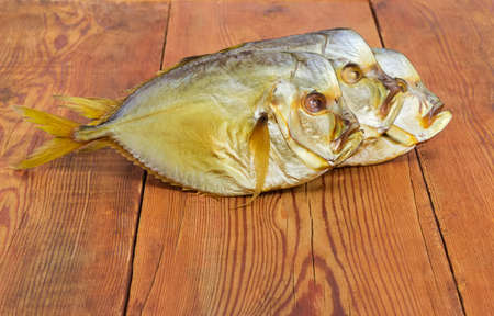 Three smoked Selene setapinnis, also known as Atlantic moonfish or Vomer setapinnis, on the old rustic table at selective focusの写真素材