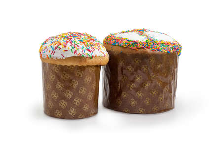 Two Easter cakes different sizes decorated with white icing and colorful sugar decors, wrapped in...