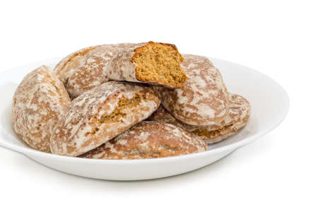 Fragment of the white dish with whole glazed gingerbreads and one broken half of gingerbread closeup...