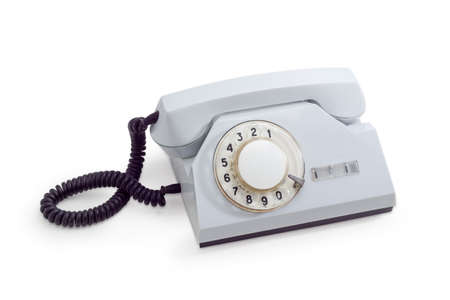 Old desktop telephone set with rotary dial in white plastic housing on a white backgroundの写真素材