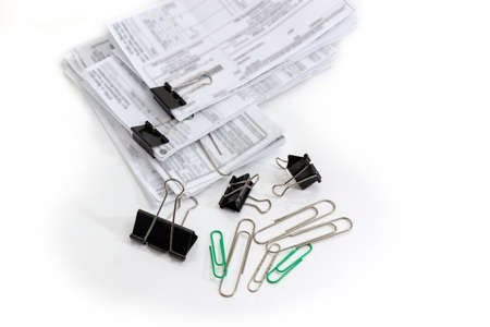 Various binder clips and wire paper clips different sizes and documents with blurred text binded using these clips on a white background
の写真素材