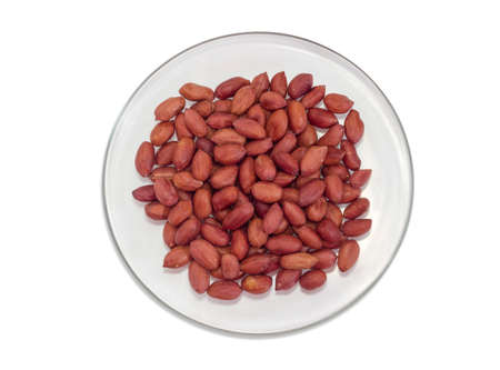 Top view of glass dish with dry roasted peanuts peeled from shells on a white backgroundの写真素材