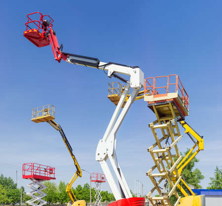 Fragment of top parts different self propelled articulated boom lifts and scissor lifts on background of clear sky
の写真素材